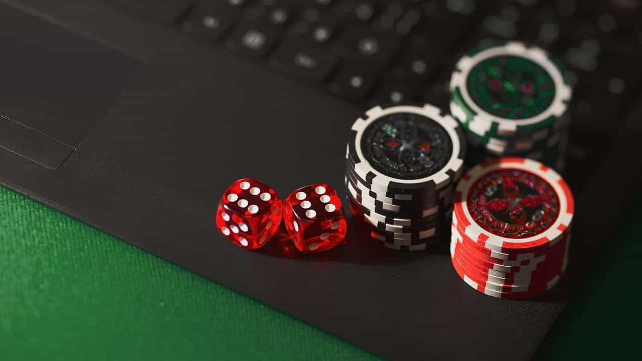 Dos dados y tres pilas de fichas de casinos sobre un teclado de computador.