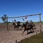 Tres gauchos argentinos corriendo carreras de caballos en los campos de la pampa.