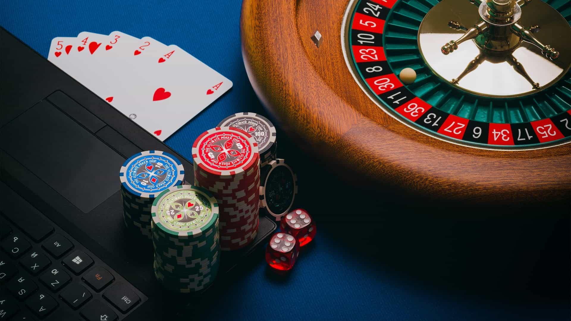 Ruleta, cartas y fichas de póker y ordenador portátil.