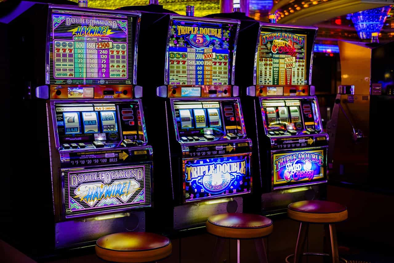 Tres máquinas tragaperras de colores brillantes en un casino.