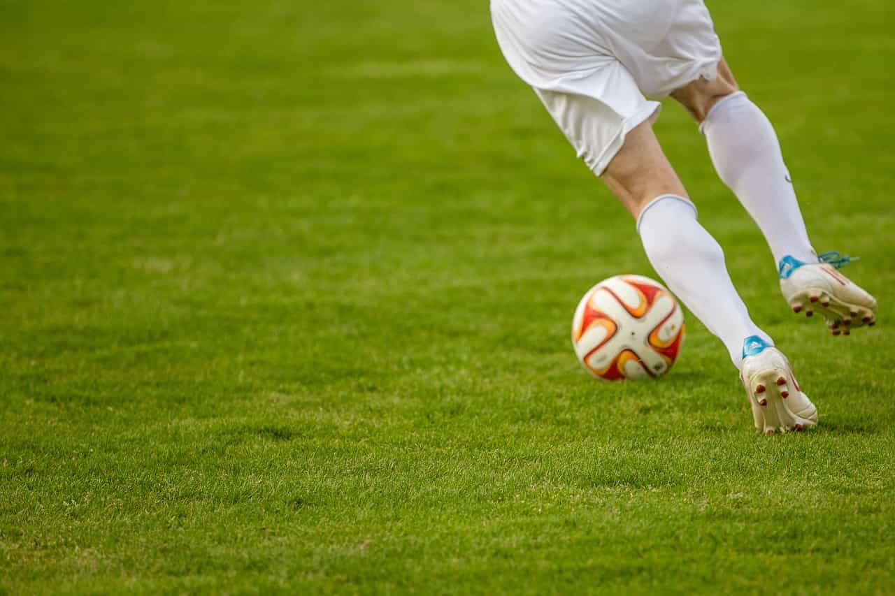 Parte inferior de un jugador de fútbol corriendo en control del balón.