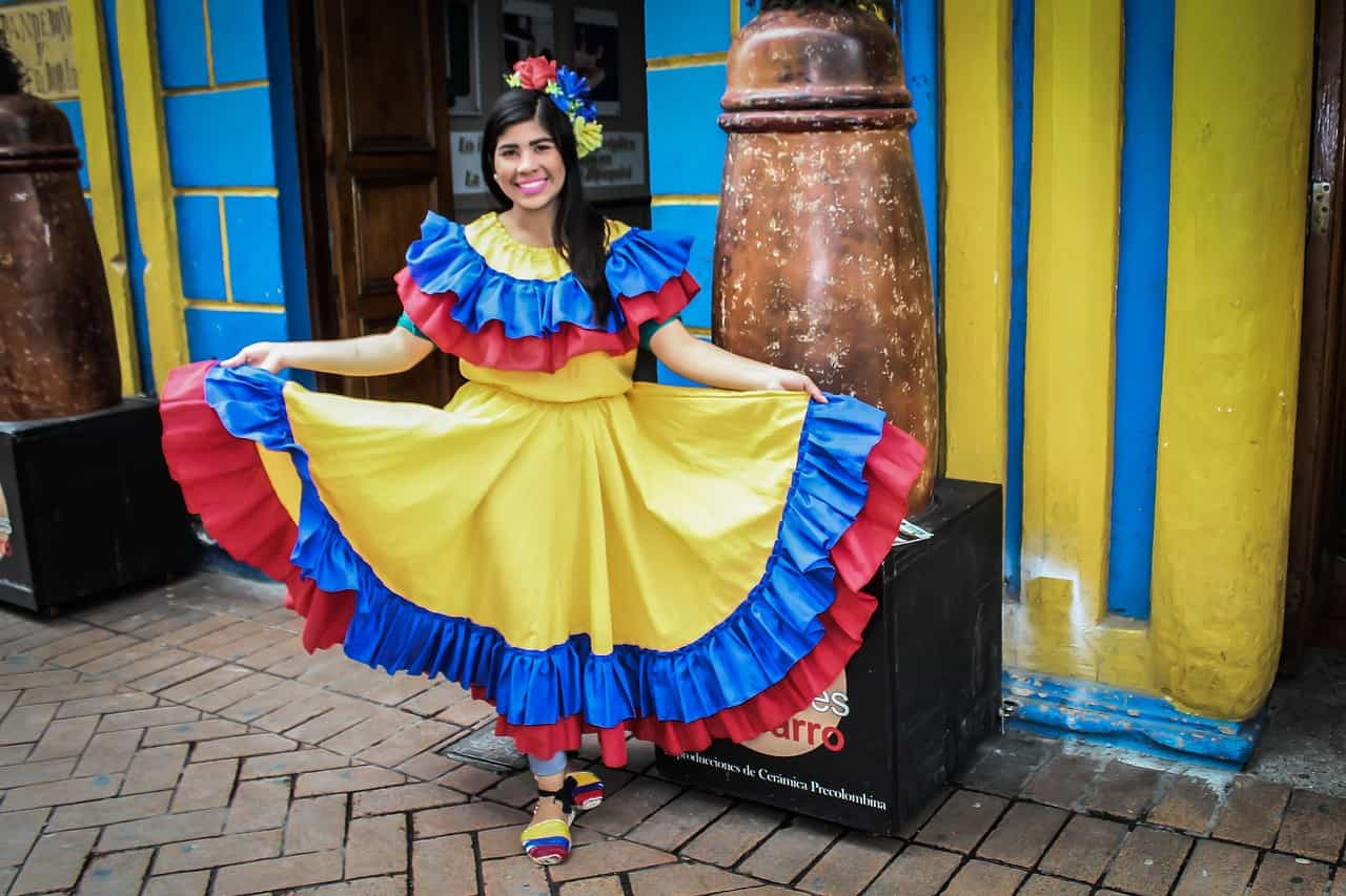 Mujer colombiana sonriendo, vestida con traje típico con los colores de la bandera.