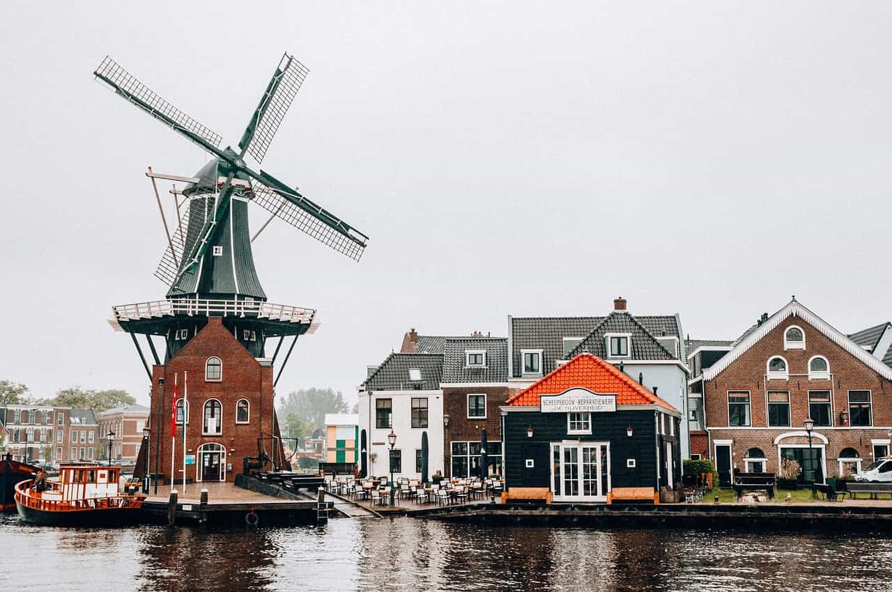 Típico paisaje neerlandés, con un molino de viento y casas de colores junto a un canal.