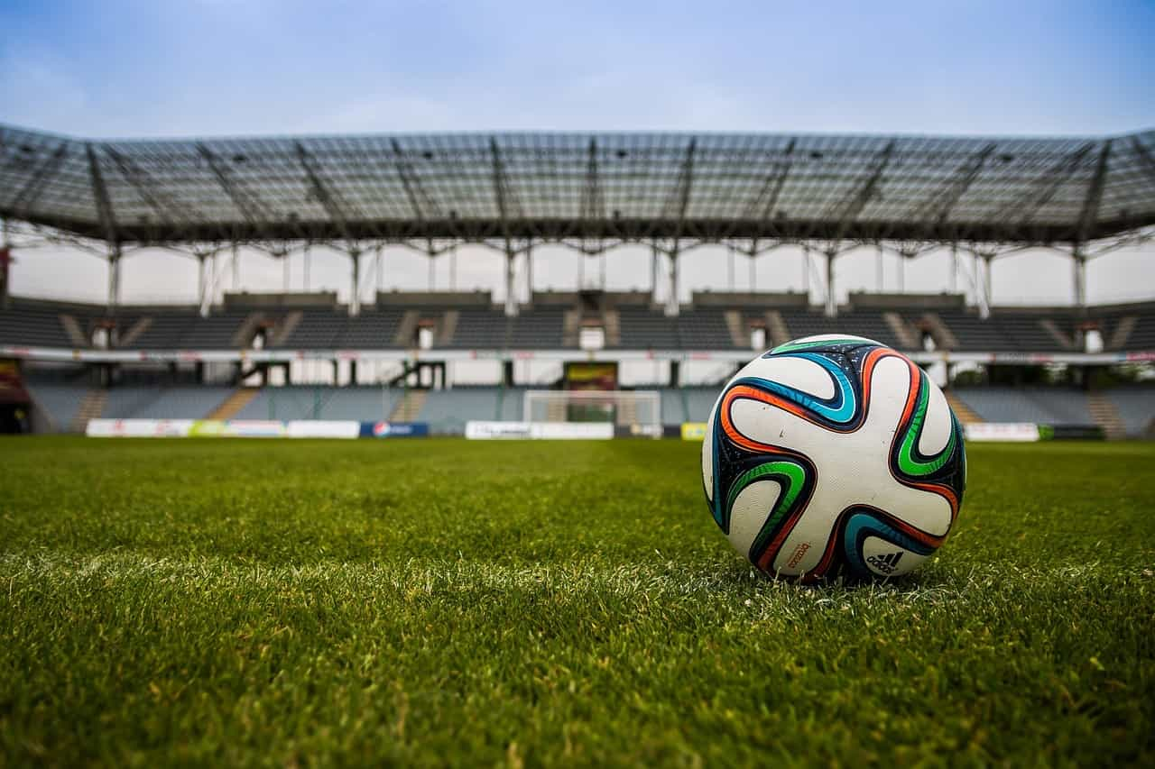 Balón de fútbol en el gramado de un estadio vacío.