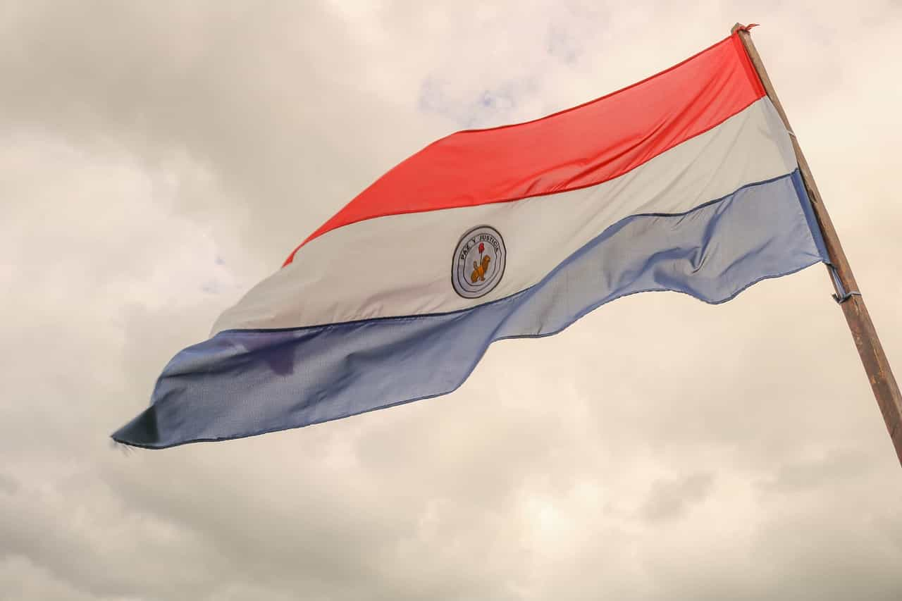 Bandera de Paraguay ondeando sobre cielo nublado.