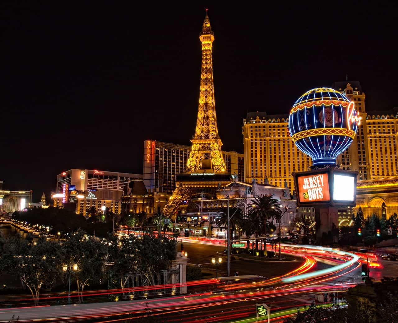 Torre Eiffel de Las Vegas, rodeada de hoteles y casinos con luces de colores en la noche.