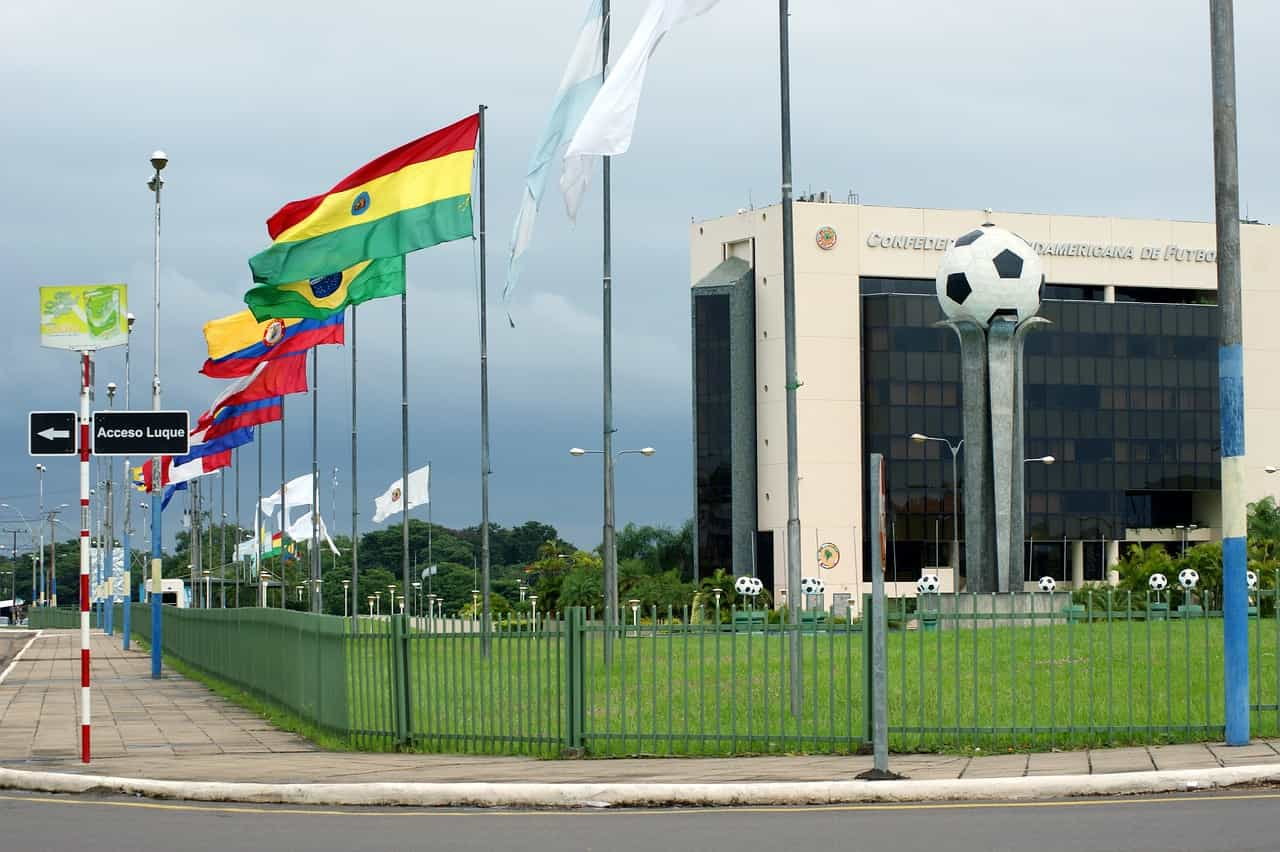 Sede de la CONMEBOL con las banderas de países latinoamericanos en mástiles.