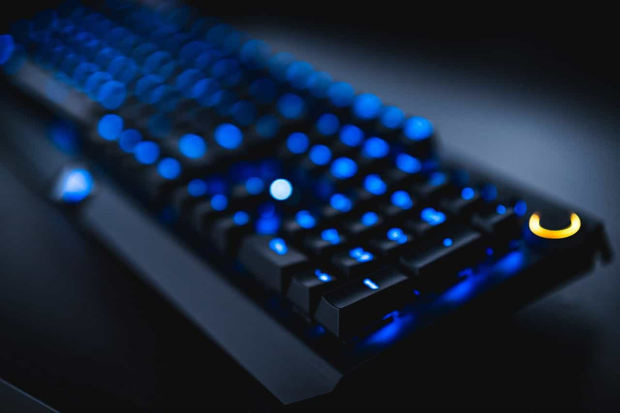 Teclado de computadora negro iluminado por luz interna azul.