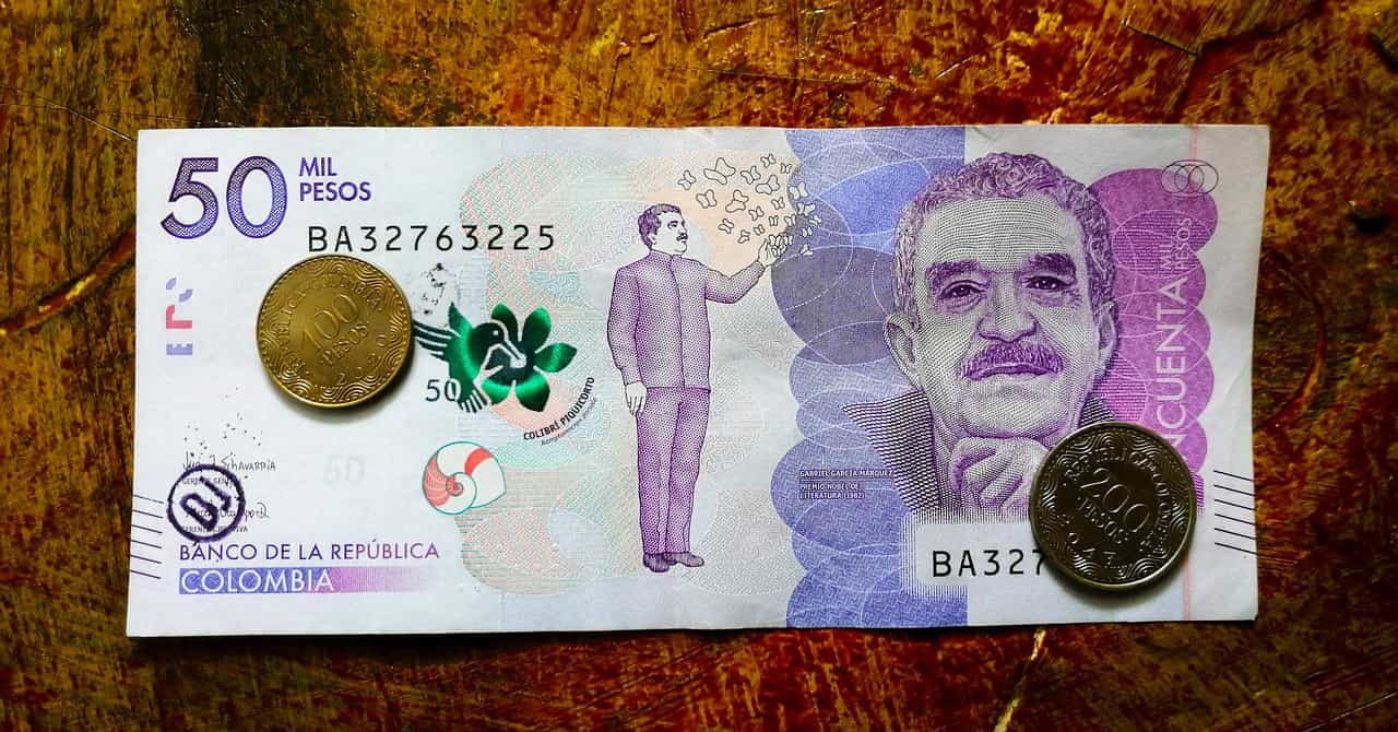 Billete de 50 mil pesos colombianos sobre el que descansan dos monedas.