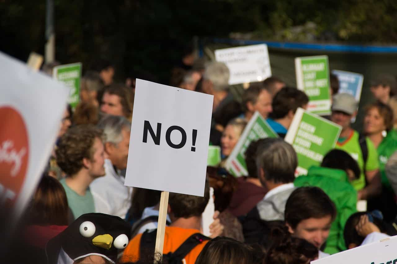 Gente manifestándose en una movilización. En un cartel se lee “No”.