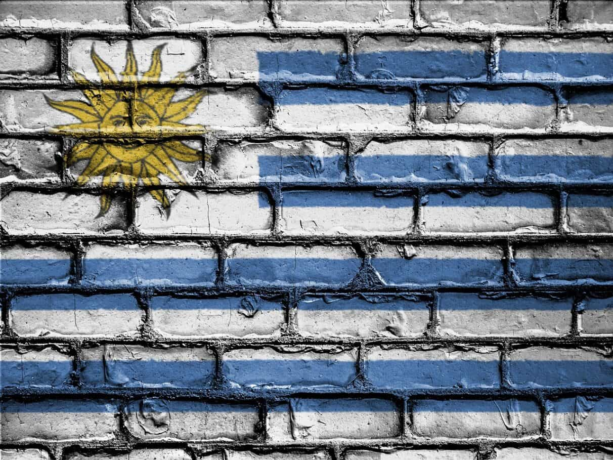 Bandera de Uruguay pintada sobre pared de ladrillos.