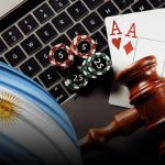 Teclado de un ordenador portátil con fichas y cartas de casino y bandera argentina.